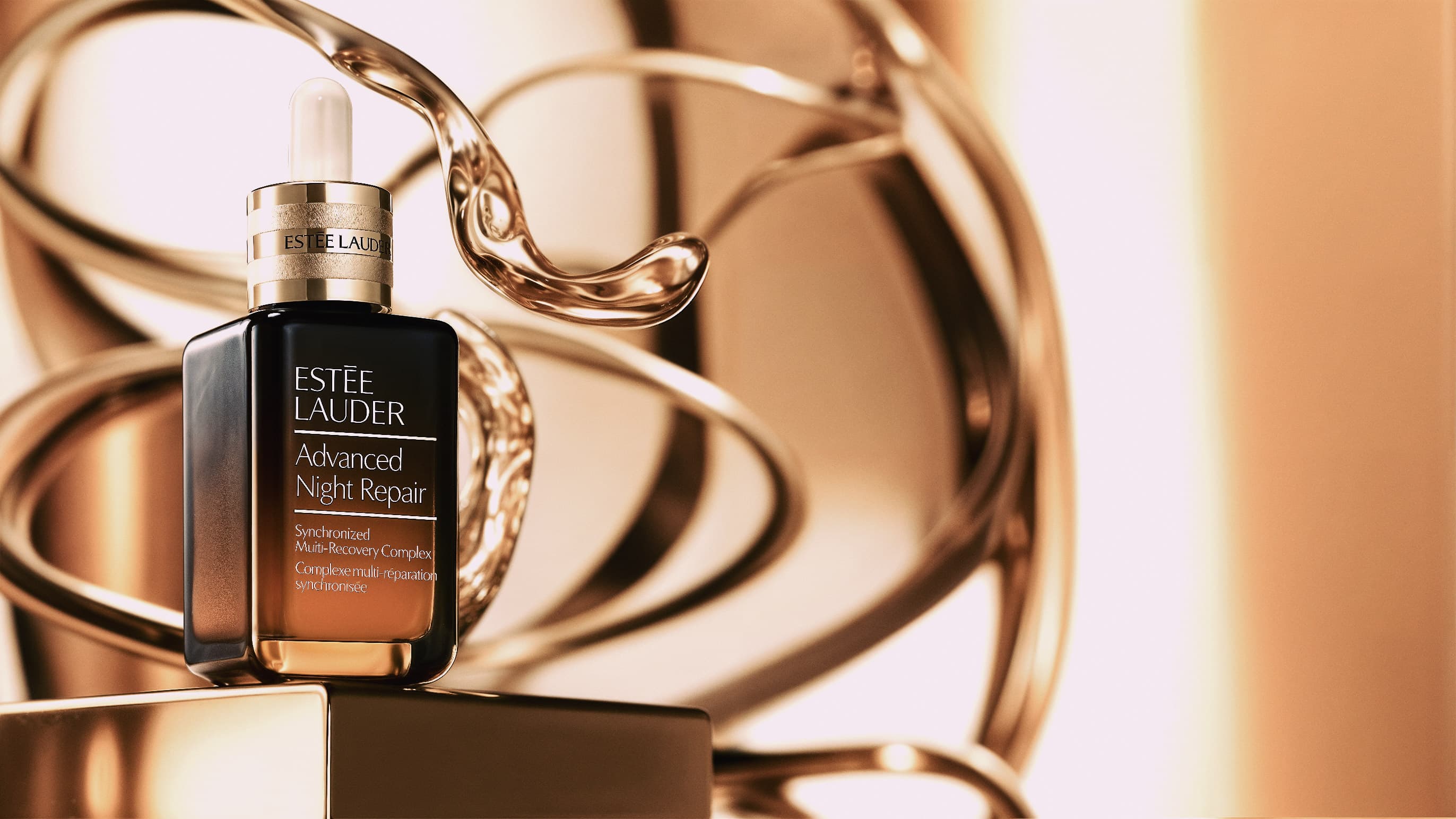 Estee Lauder serum on a gold plinth before a polished gold ribbon sculpture